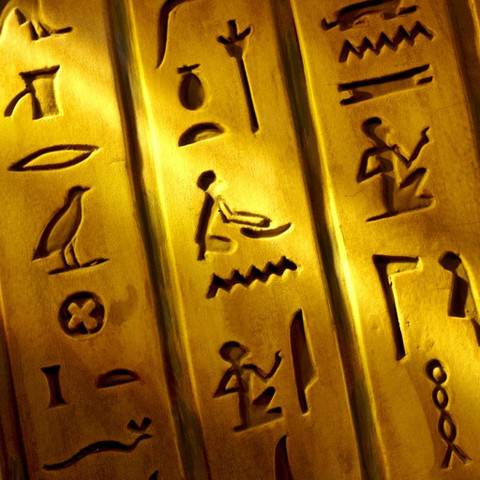 Close up shot of Egyptian hieroglyphics carved into stone with shaft of light
